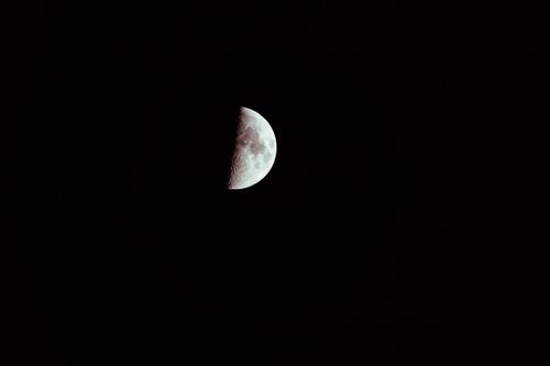 Free A striking photograph of a half moon in the dark night sky, showcasing lunar details. Stock Photo