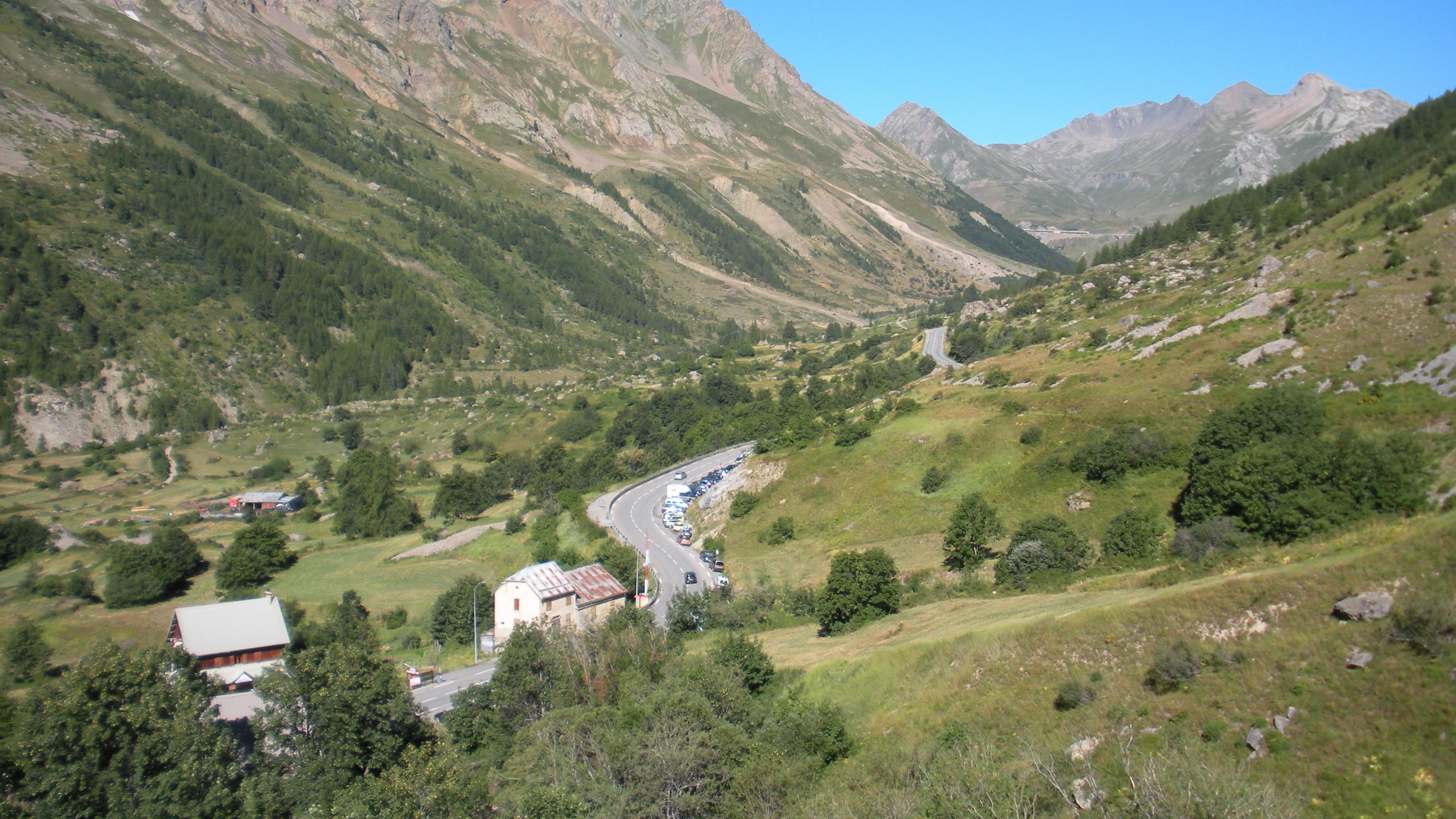 Picturesque mountain valley with winding road and lush greenery during the day.