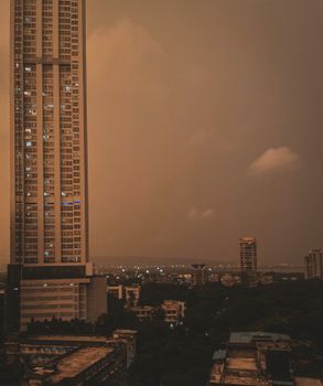Aerial view of a cityscape featuring a towering skyscraper against a dramatic dusk sky.
