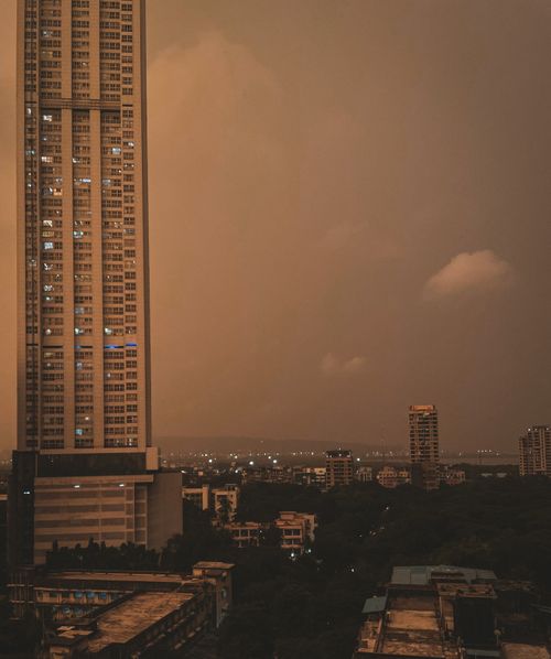 Free Aerial view of a cityscape featuring a towering skyscraper against a dramatic dusk sky. Stock Photo