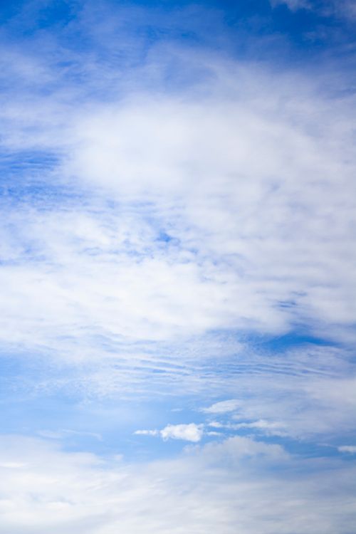Free A serene view of a bright blue sky dotted with soft white clouds, perfect for backgrounds. Stock Photo