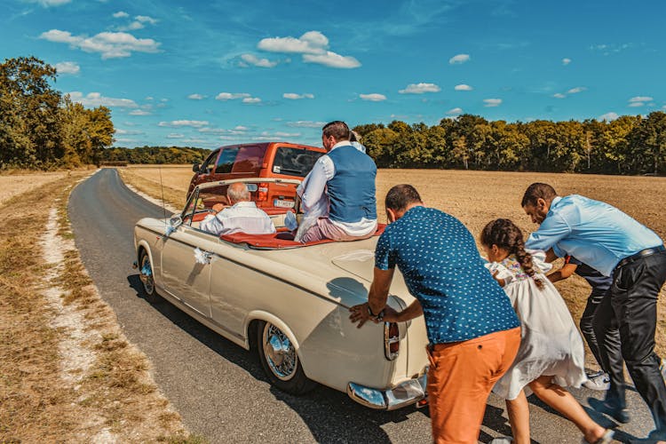 People Pushing A Vintage Car