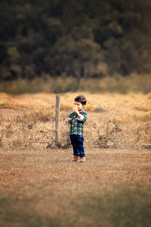 A Young Boy Standing on Brown Field