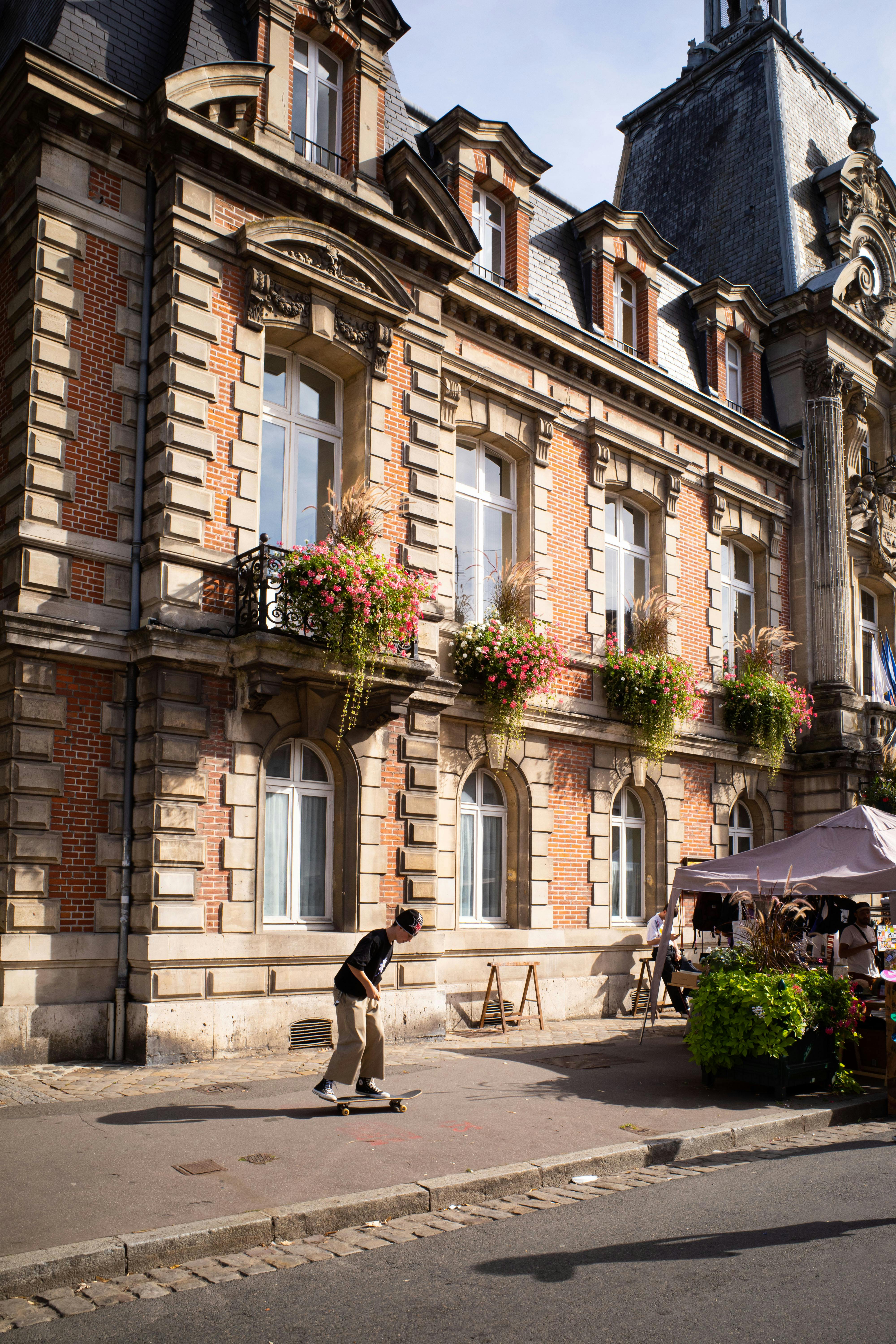 A skateboarder in front of a classic French building in Fontainebleau, France, highlights urban street life.