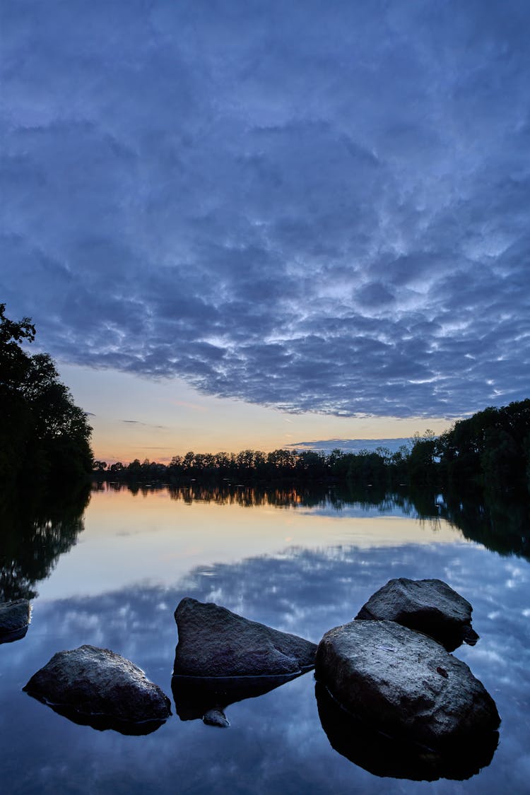 Rocks On Body Of Water Under Cloudy Sky