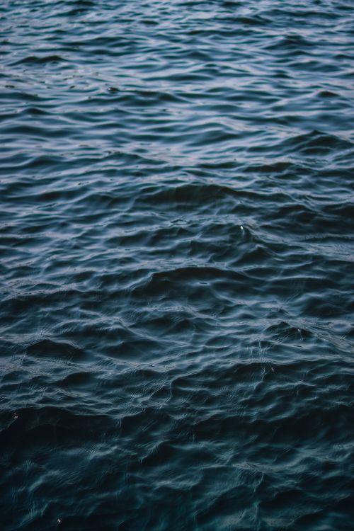 Free A serene close-up of deep blue ocean waves with textured ripples, perfect for background use. Stock Photo