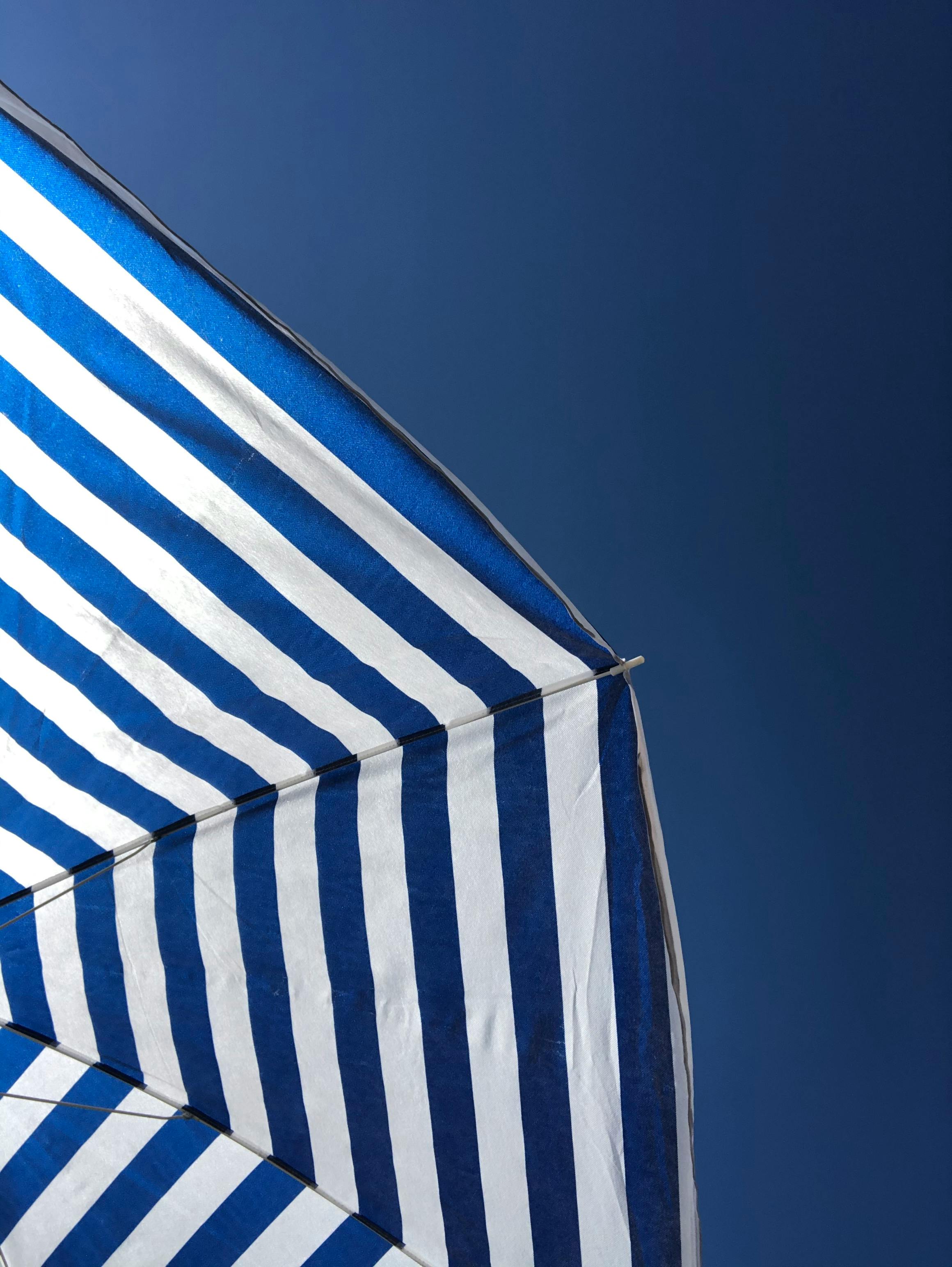A close-up of a striped beach umbrella set against a clear blue sky in Peloponnes, Greece.