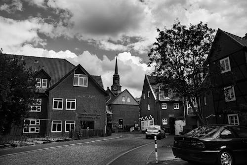 Grayscale Photo of Houses Near a Clock Tower