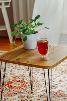 Cozy living room interior featuring a wooden table with a cup of tea and a houseplant.