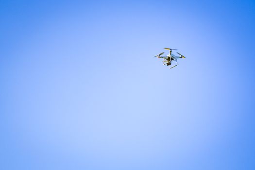 A drone flying in a clear blue sky, displaying modern technology and innovation.