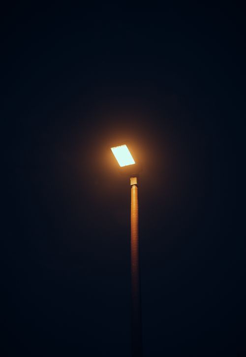 Free Tall street lamp glowing softly against a dark night sky, creating a tranquil urban scene. Stock Photo