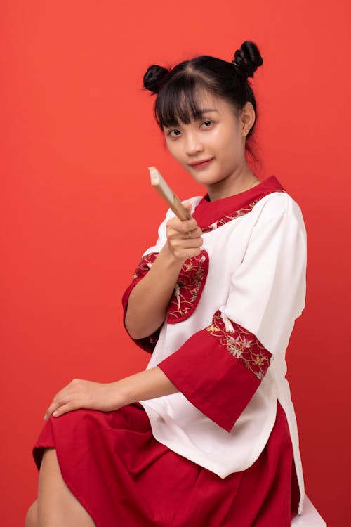 Woman in Traditional Wear Holding a Hand Fan