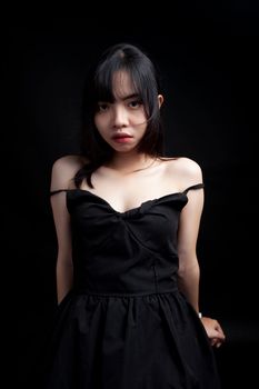 Studio portrait of a woman in a black dress against a dark background, showcasing fashion elegance.