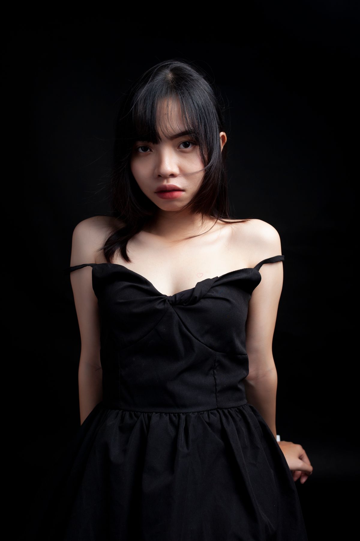 Studio portrait of a woman in a black off-shoulder dress