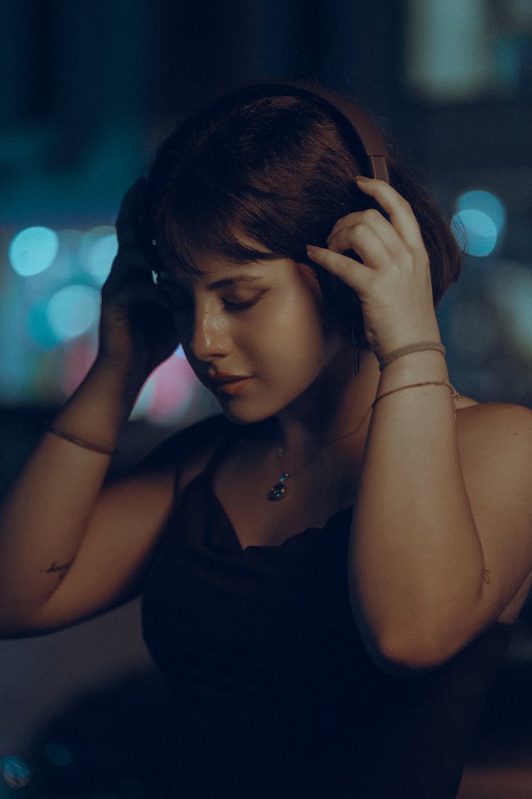 A Woman In Black Tank Top Wearing Headphones