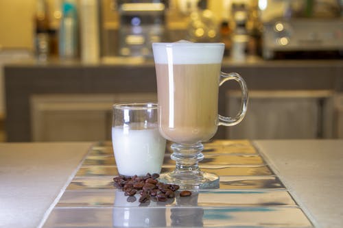 A Drinking Glass with Milk Beside the Glass Mug with Coffee