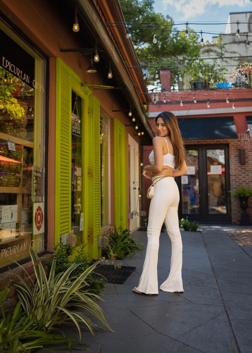Free Stylish woman in white outfit posing outdoors on a city street, looking over shoulder. Stock Photo