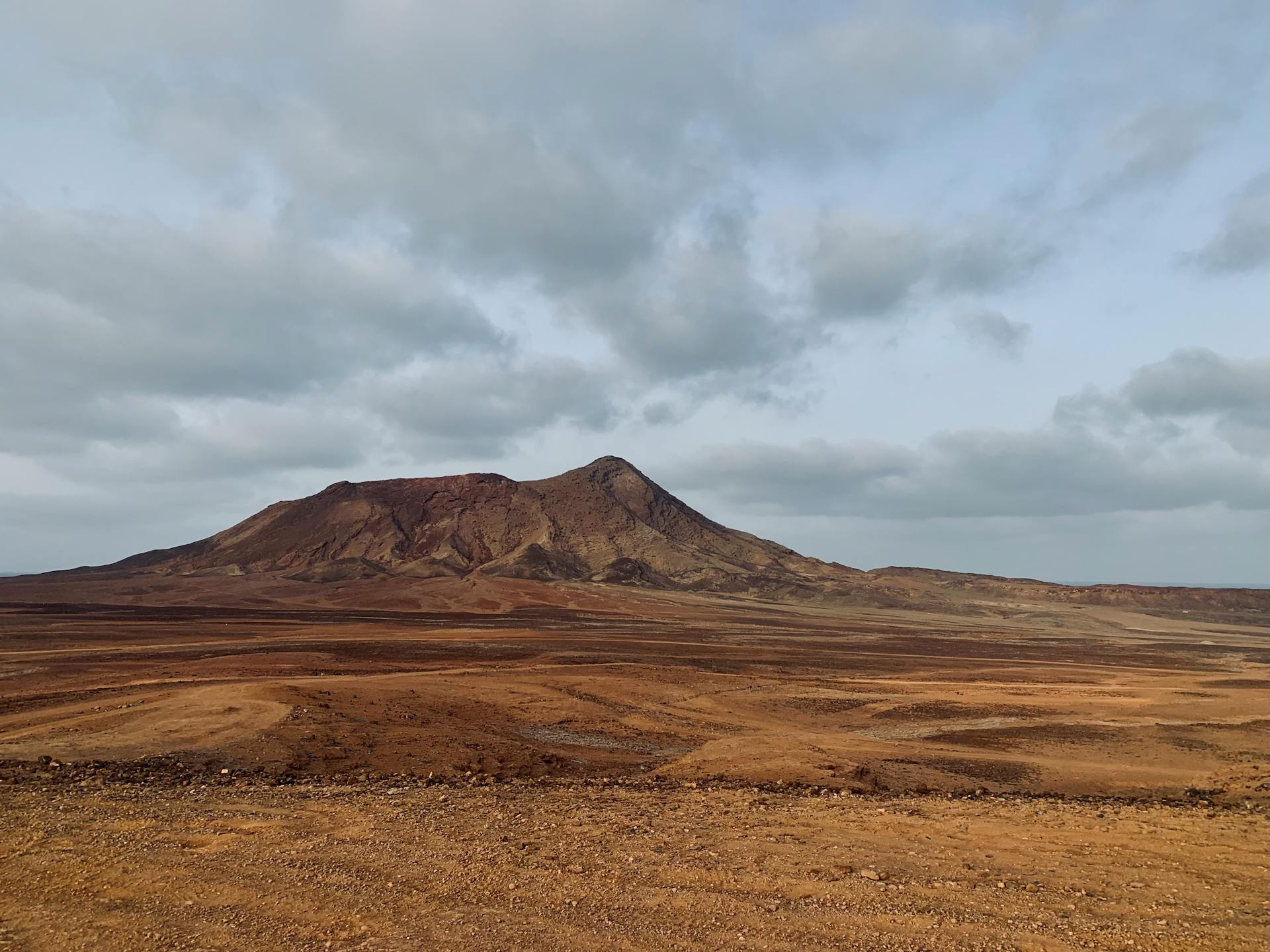 Barren land with dramatic mountain under cloudy sky in Sal, Cape Verde.