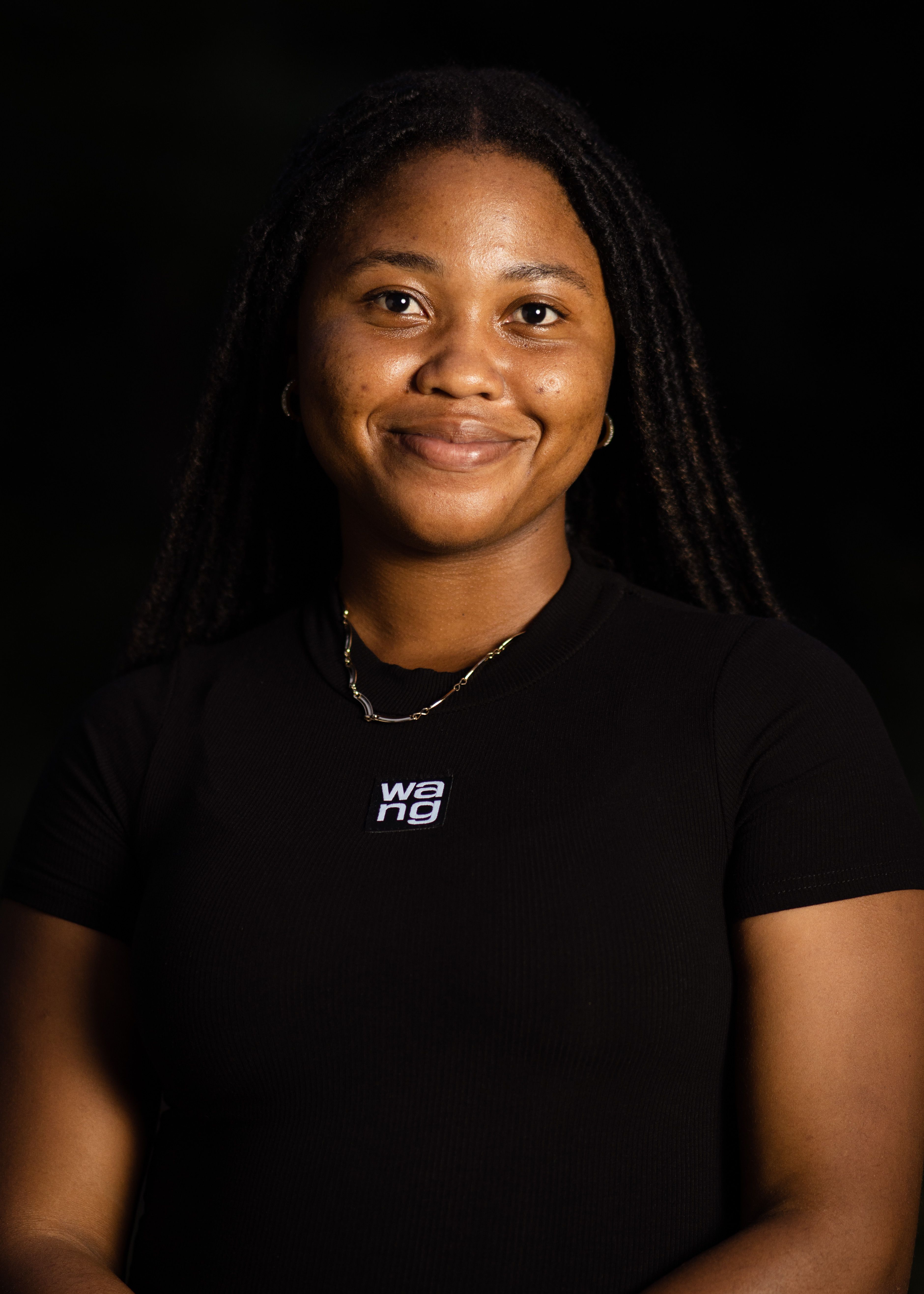 Confident black woman smiling in a studio portrait with a dark background.