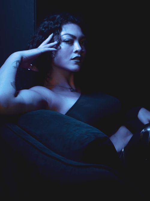 Free Artistic portrait of a woman with curly hair in a dramatic, low-light setting. Stock Photo