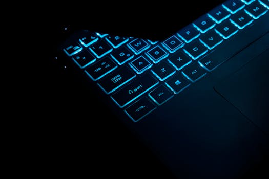 Close-up of a glowing laptop keyboard in dark, showcasing illuminated keys and sleek design.