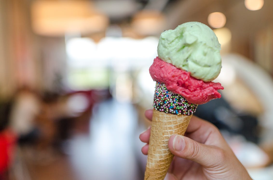 Close-up Photo of Person Holding Assorted-flavor Ice Cream on Cone