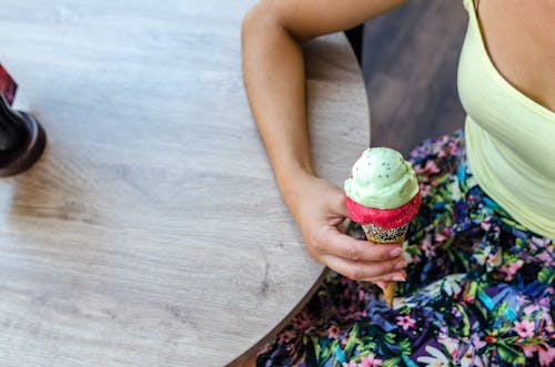 Женщина, сидящая, держа мороженое возле стола
