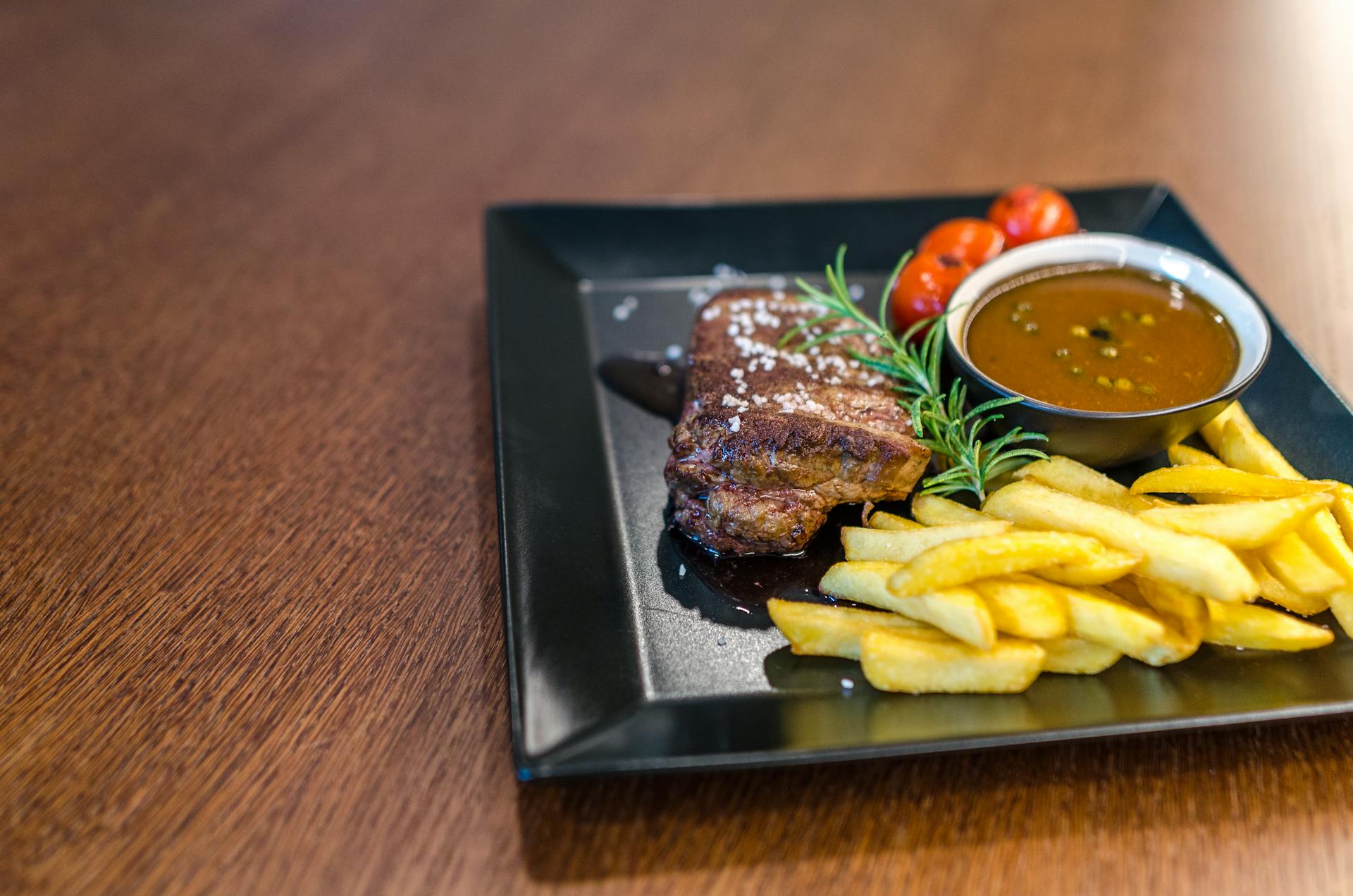 Grilled Beef With Fries and Sauce on Black Ceramic Plate