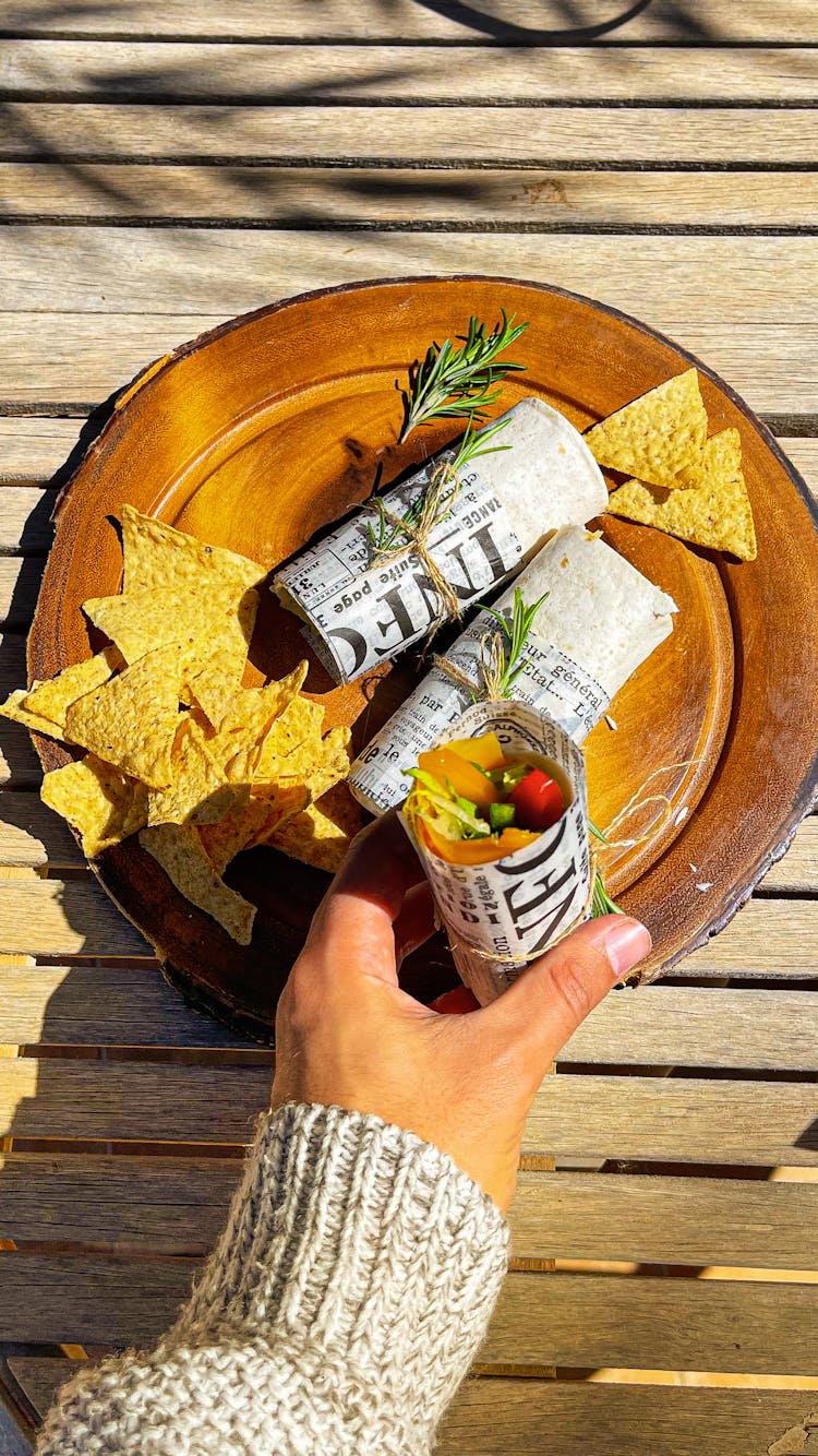 Person Hand Holding Snack Rolls On Plate