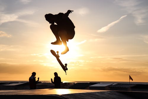 Skateboarder Jumping Over a Ramp During Sunset