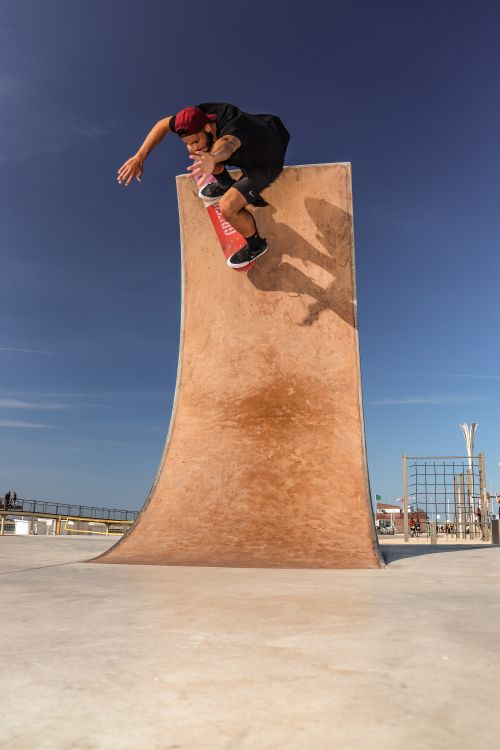 Free Dynamic action shot of a skateboarder mid-trick on a ramp in Calais, France, against a clear blue sky. Stock Photo