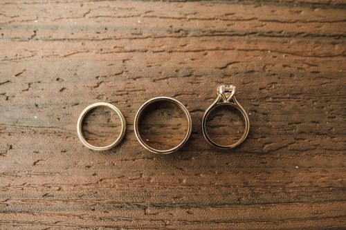 Free Close-up of gold and diamond rings displayed on a rustic wooden surface. Stock Photo