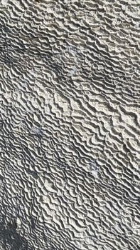 Close-up of a rock surface showcasing unique wavy texture patterns and shades of gray.