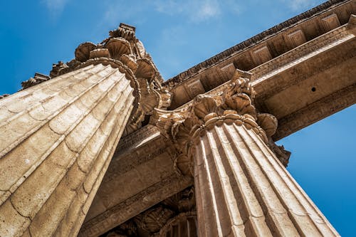 Low Angle Photography of Brown Pillars Under White Sky