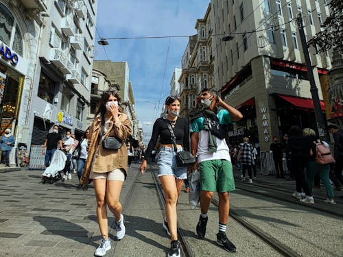 A Group of People Walking on the Street while Wearing Face Masks