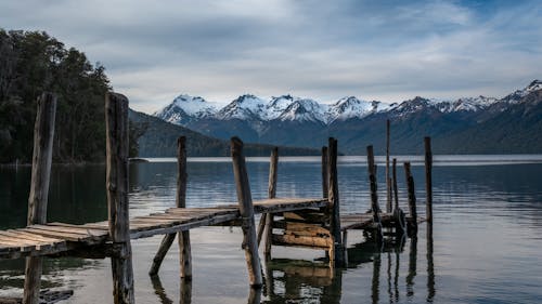 Brown Wooden Dock on Lake Near Snow Covered Mountain