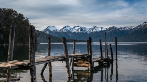 Free Serene lakeside view with snow-capped mountains and rustic wooden dock. Stock Photo