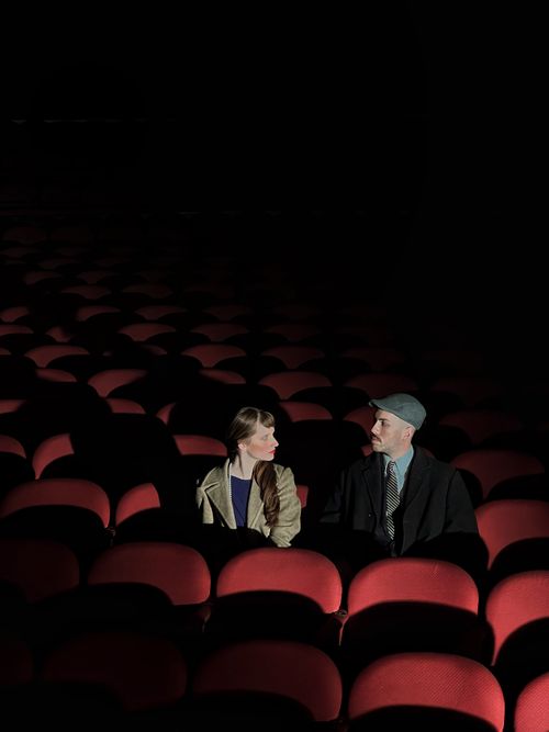 Free A couple seated in a dark, empty theater, creating a dramatic, intimate atmosphere. Stock Photo
