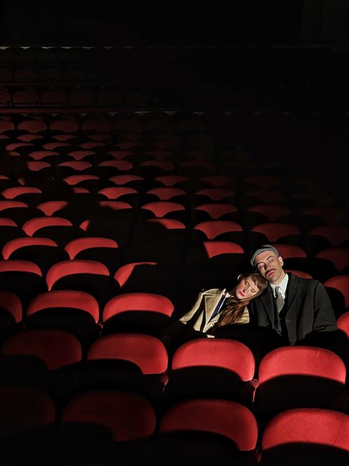 Free A couple sits in dimly lit auditorium seats, creating a serene and intimate moment. Stock Photo