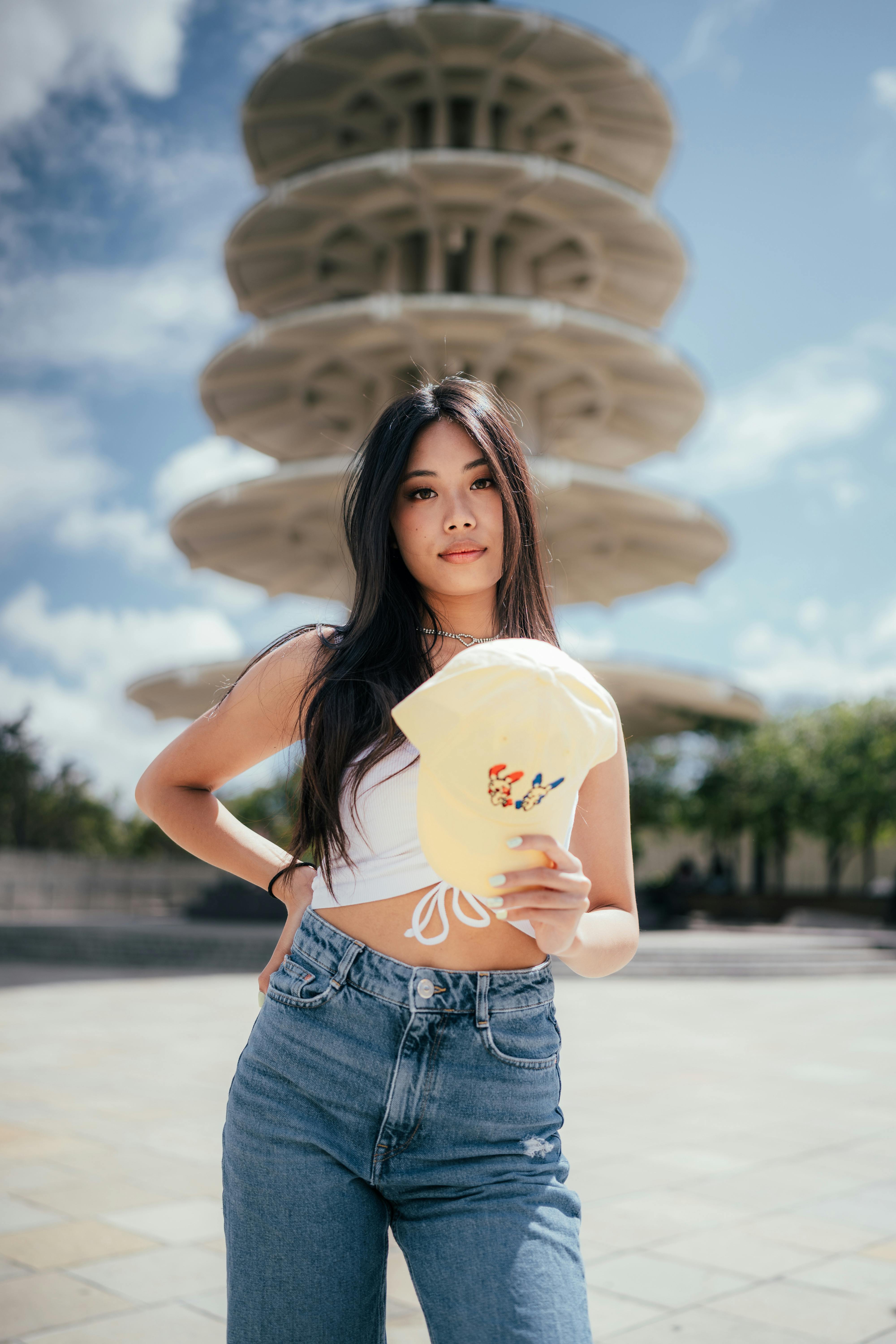 Free Confident woman holds cap in front of iconic tower, stylish portrait. Stock Photo