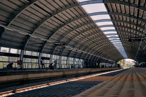 Free Modern railway station platform with curved steel roof and waiting passengers. Stock Photo