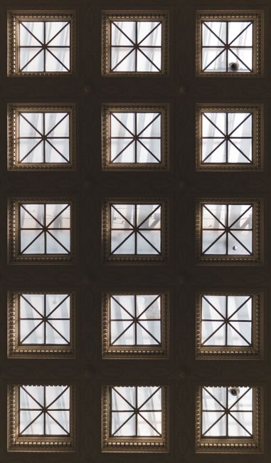 Photo of a symmetrical ceiling featuring square geometric window patterns with intricate designs.