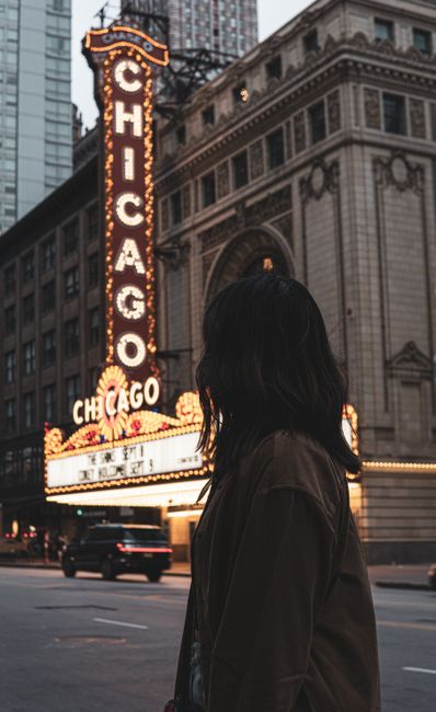 View of an illuminated Chicago Theatre sign with a silhouette woman at night.