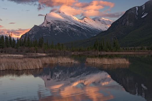 Breathtaking sunset over snow-capped Banff mountains reflecting on a serene lake.