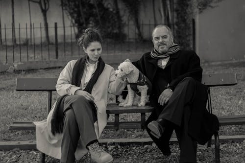 Grayscale Photo of a Couple Sitting with Their Dog