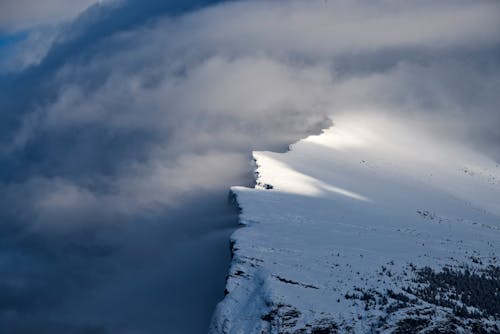 Aerial View of a Snowy Mountain Peak in Fog 