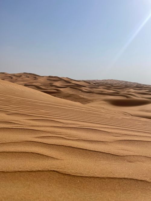 Free Golden sand dunes in Dubai under a clear blue sky offer a breathtaking desert landscape. Stock Photo