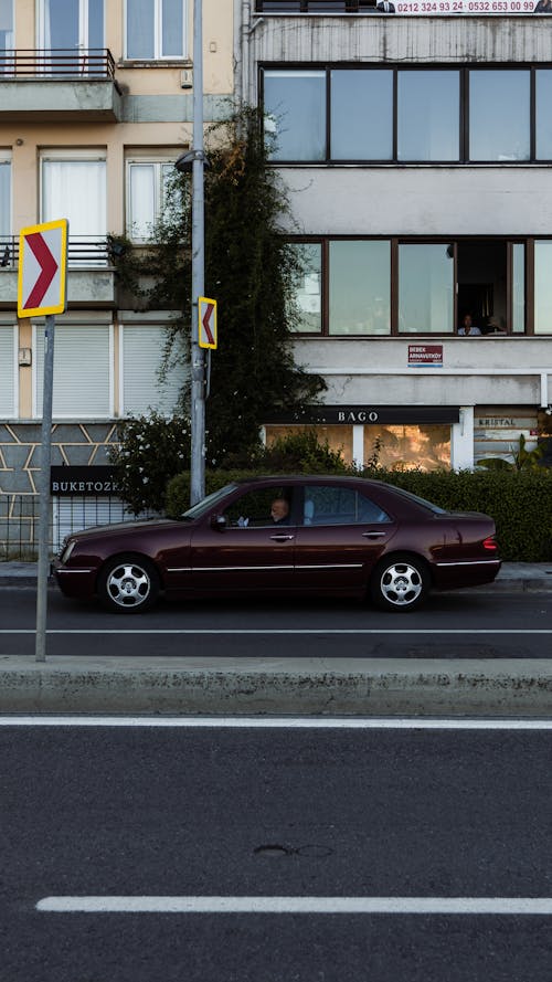 Red Sedan Parked in Front of White Building