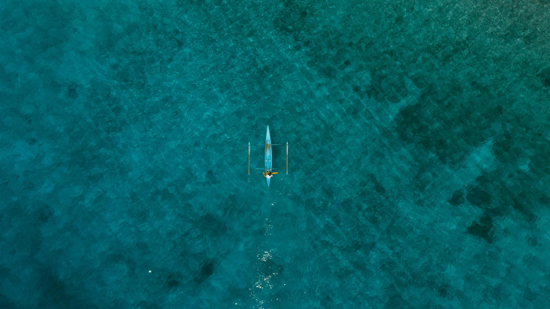 Stunning drone shot of a solitary boat on blue waters near Padre Burgos, Philippines.