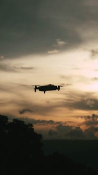 Silhouetted drone flying against a dramatic sunset sky in Tanauan, Philippines.